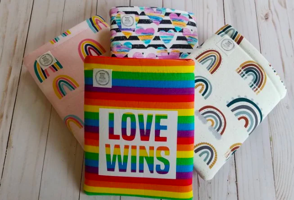 Four fabric book sleeves, all with different rainbow designs. The top one says 
