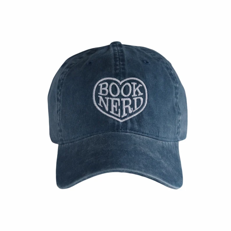 Image of a dark blue vintage style baseball hat with the words "book nerd" inside a heart in white. 