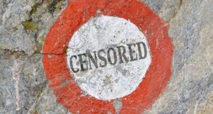 the word "censored" in black text inside a white circle with a red ring around it, all painted on a stone surface