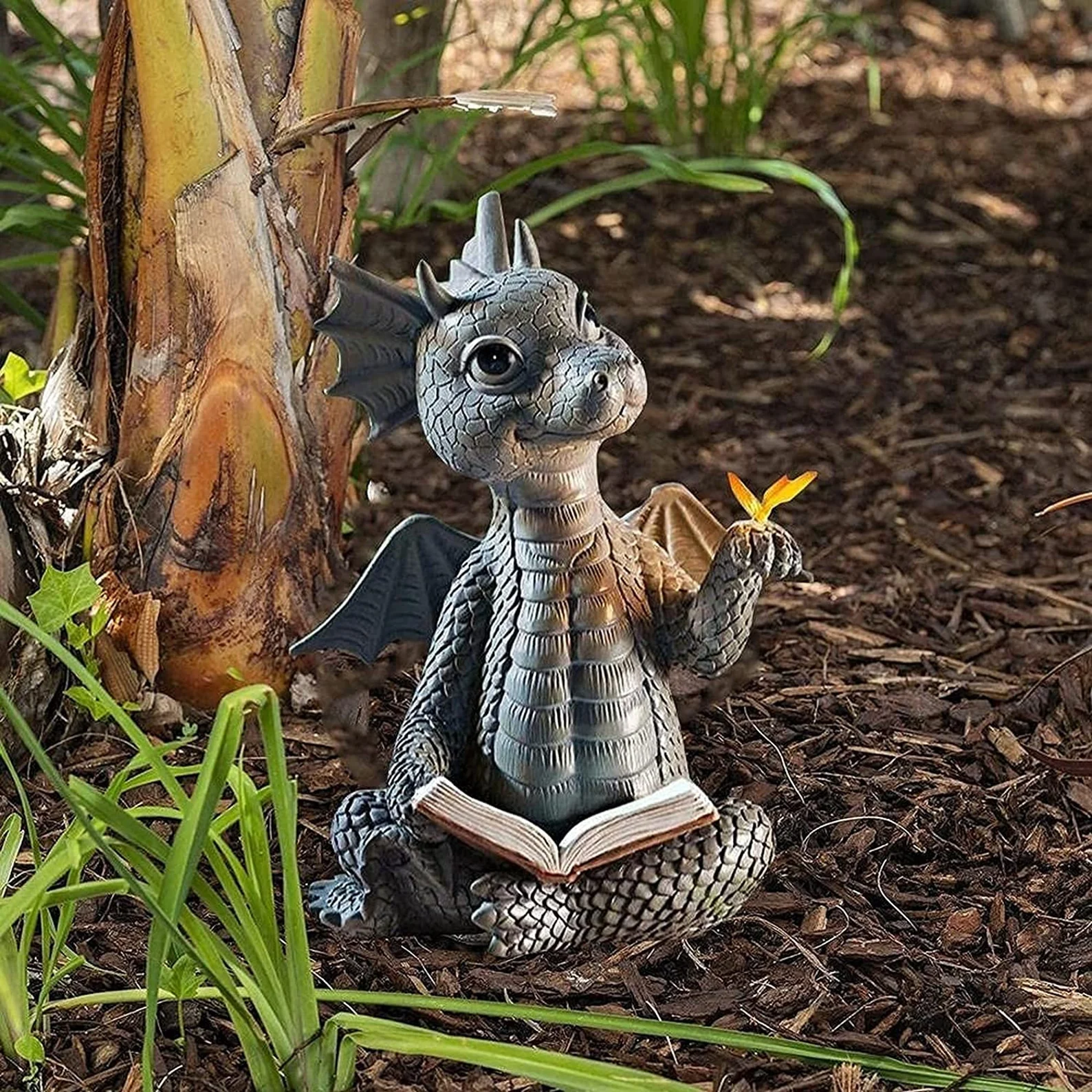 A small silver statue of a smiling dragon with a book open in its lap.