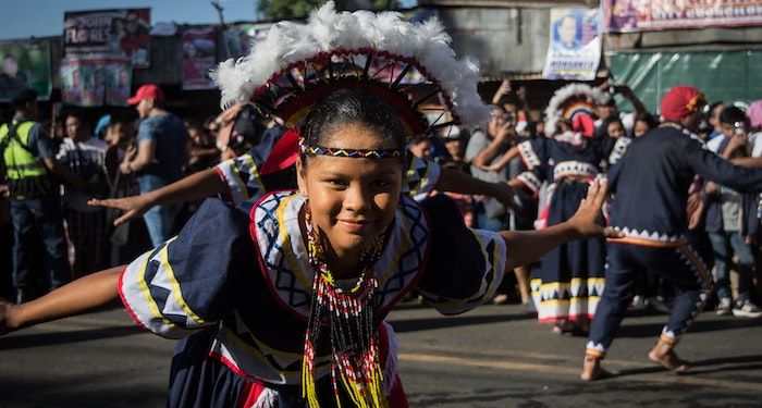 a photo of a Filipino woman dancing wearing regalia