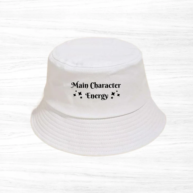 Image of a white bucket hat with the words "main character energy" in black. 