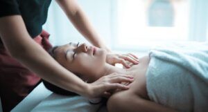 a photo of a woman laying on her back with her eyes closed getting her shoulders massaged