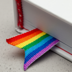 a photo of a white book with a rainbow ribbon bookmark