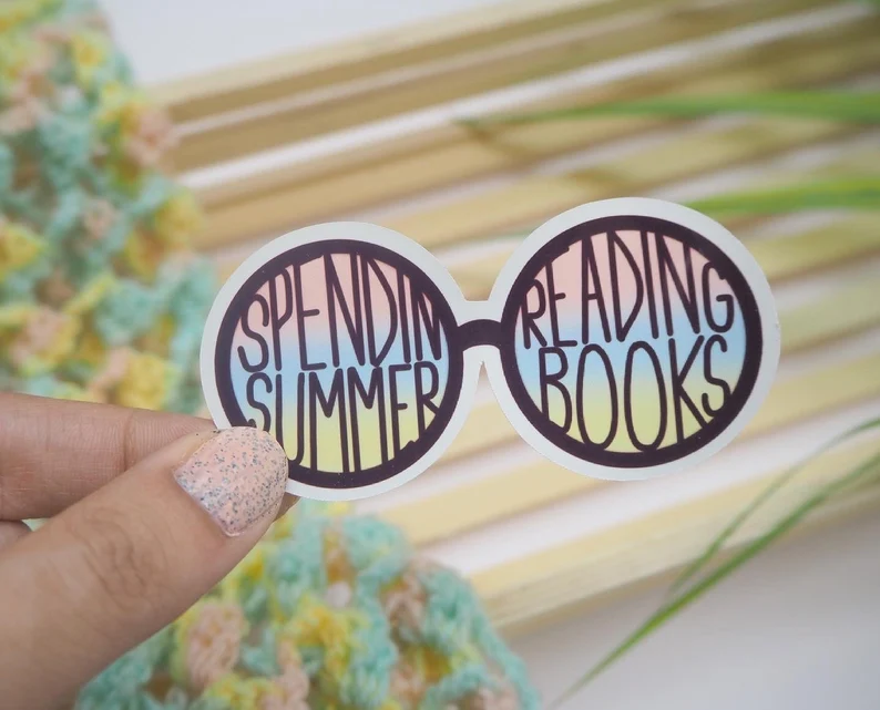 Image of a sticker in the shape of glasses. Inside the lenses are the words "spend summer reading books."