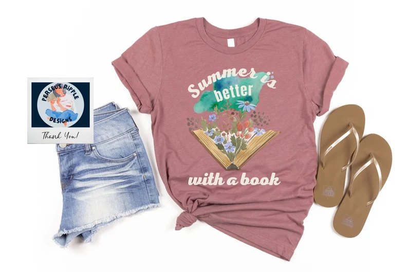 Image of a pink t-shirt beside flip flops and shorts. The shirt says "summer is better with a book."