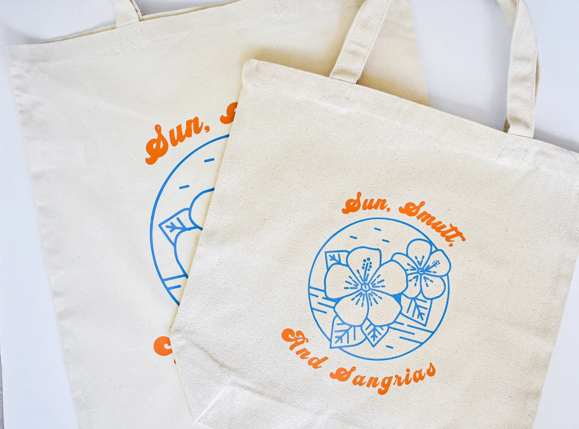 Image of a canvas tote bag. The tote reads "Sun, Smutt, and Sangrias."