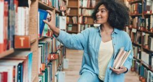 brown-skinned woman with kinky curly hair in the library smiling