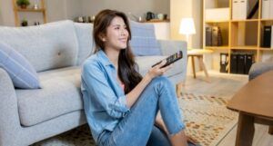 light-skinned Asian woman watching tv and smiling