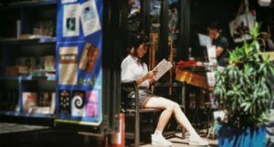 Asian woman reading in doorway of bookstore