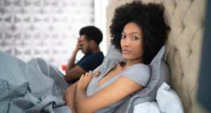 a photo of a Black couple arguing in bed