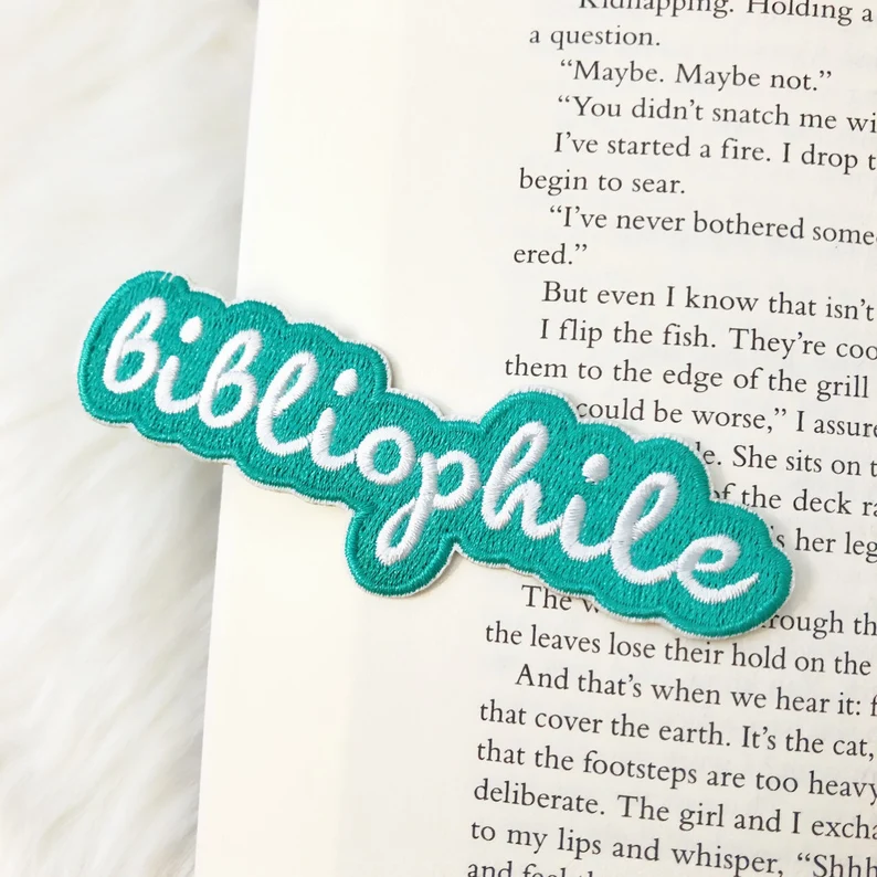 Image of a teal patch that reads "bibliophile" in white. 