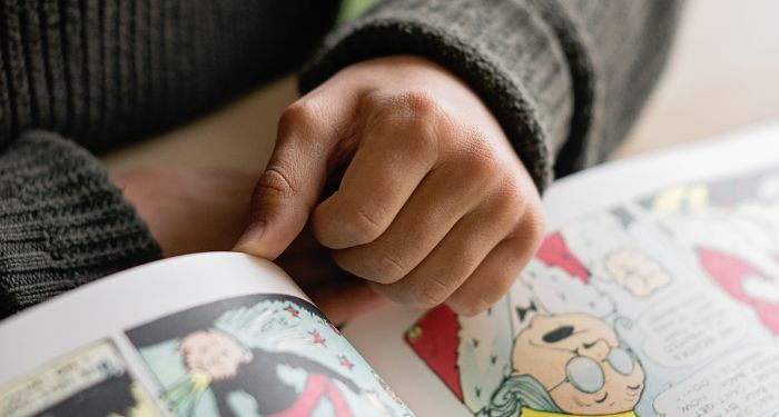 a light-skinned hand holding open a comic