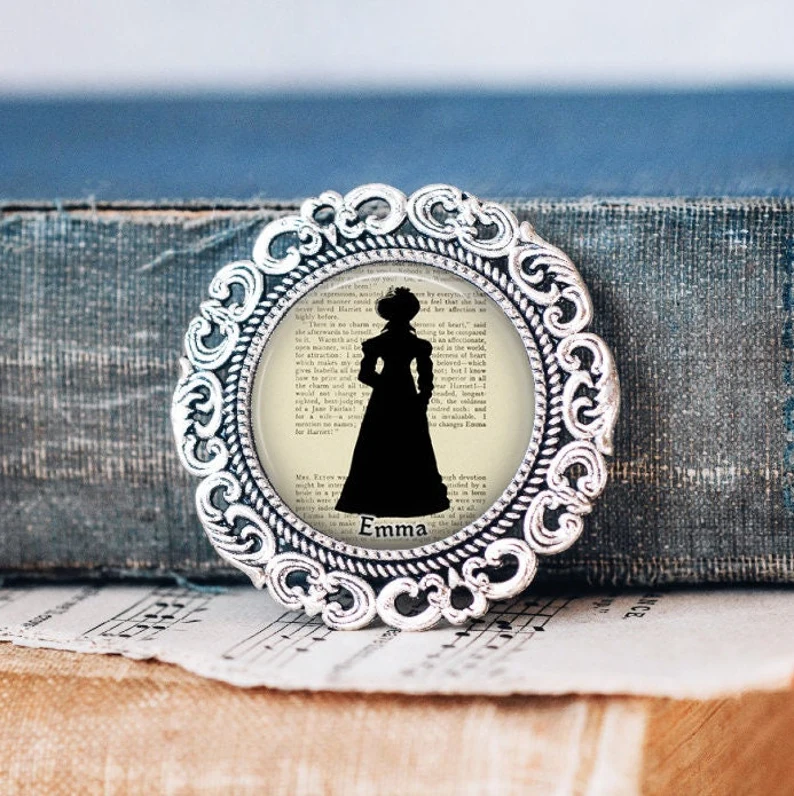 photo of a pin inspired by Emma placed against the spine of a worn out book
