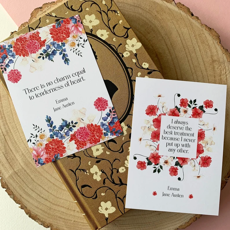 image of two cards with Emma quotes placed on a book and some wood