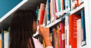 棕褐色皮肤的女孩看着书架上的书