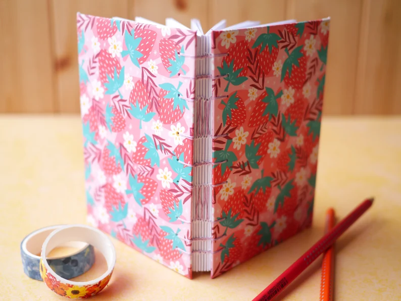 Image of a hand-stitched journal with a strawberry cover pattern. 