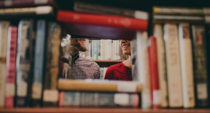 people smiling at each other through books