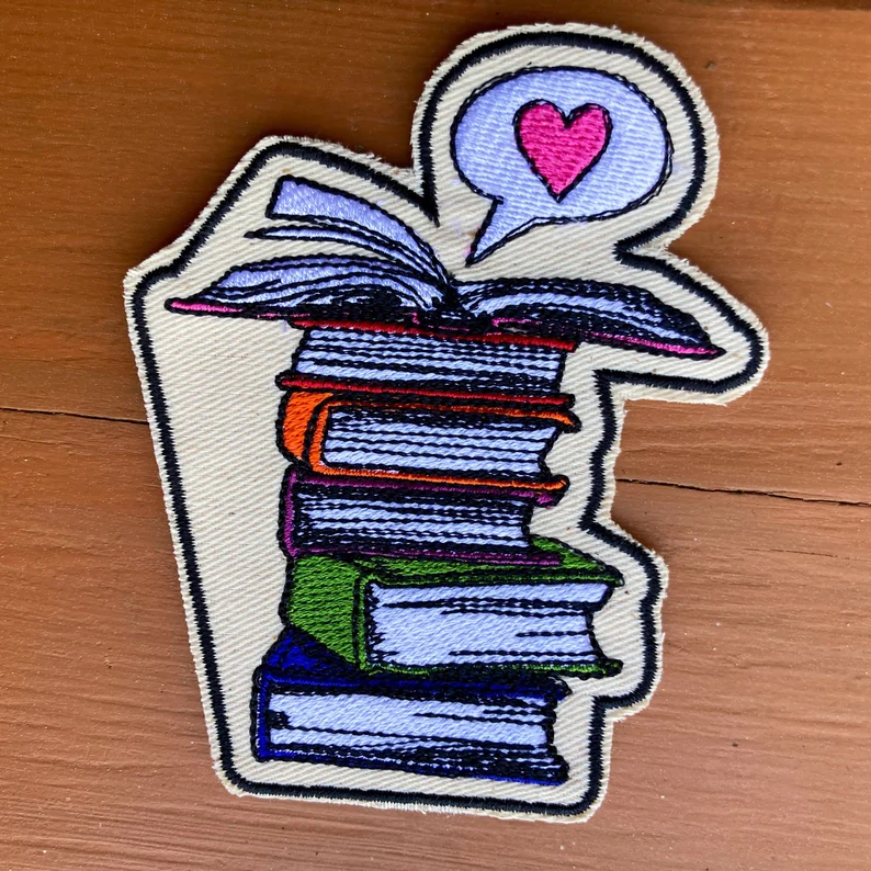 Image of a colorful stack of books. Above it is a speech bubble with a heart. 