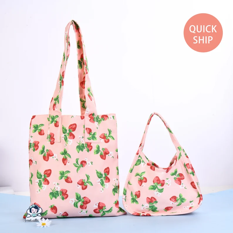 Image of two tote bags with a strawberry print. 