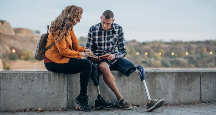 image of two individuals with limb differences reading a book