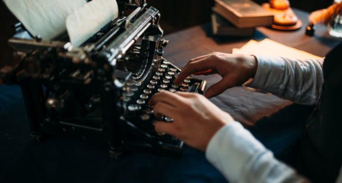 aa pair of hands typing on a black typewriter