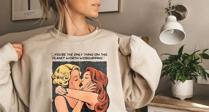 Sweatshirt with a Celia St. James and Evelyn Hugo kissing illustration and the quote, "you're the only thing on this planet worth worshipping"