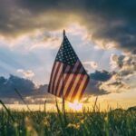 an American flag in a field of grass at sunrise