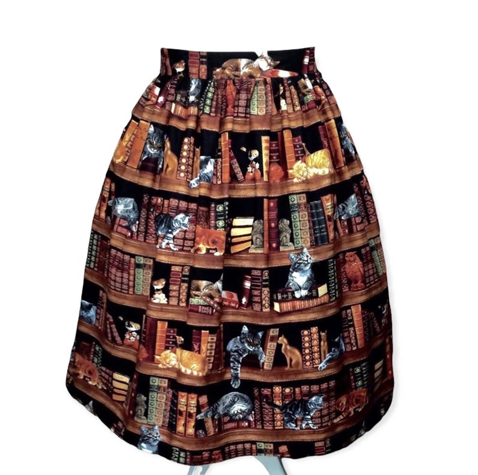 A skirt printed with a pattern of bookshelves stuffed with old-fashioned books and cats of various colors and sizes.