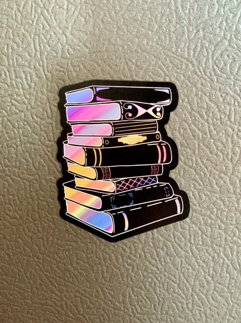 Magnet of a stack of black books with holographic-style coloring on the pages. 