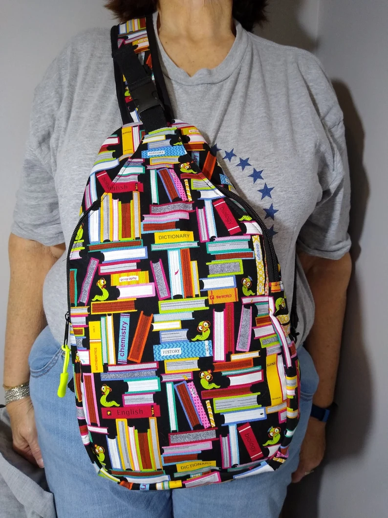 photo of a person wearing a crossbody bag with stacks of colorful books printed on it