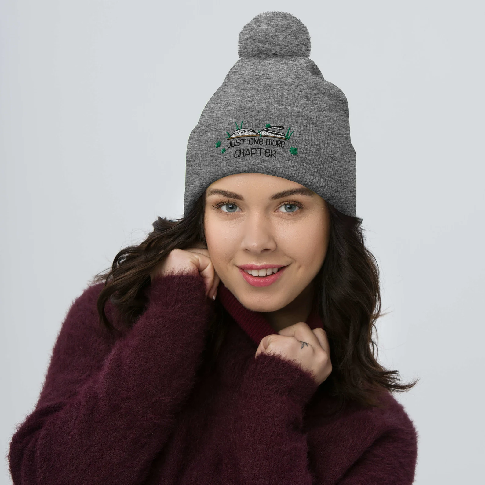 A woman wearing a gray beanie that says "Just One More Chapter".
