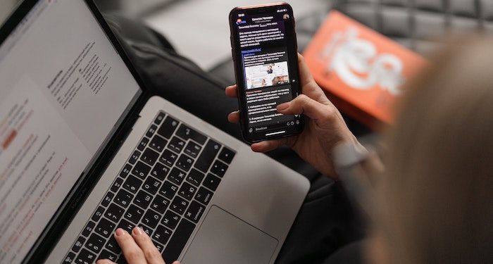 a photo of someone checking their phone as they are typing on a laptop