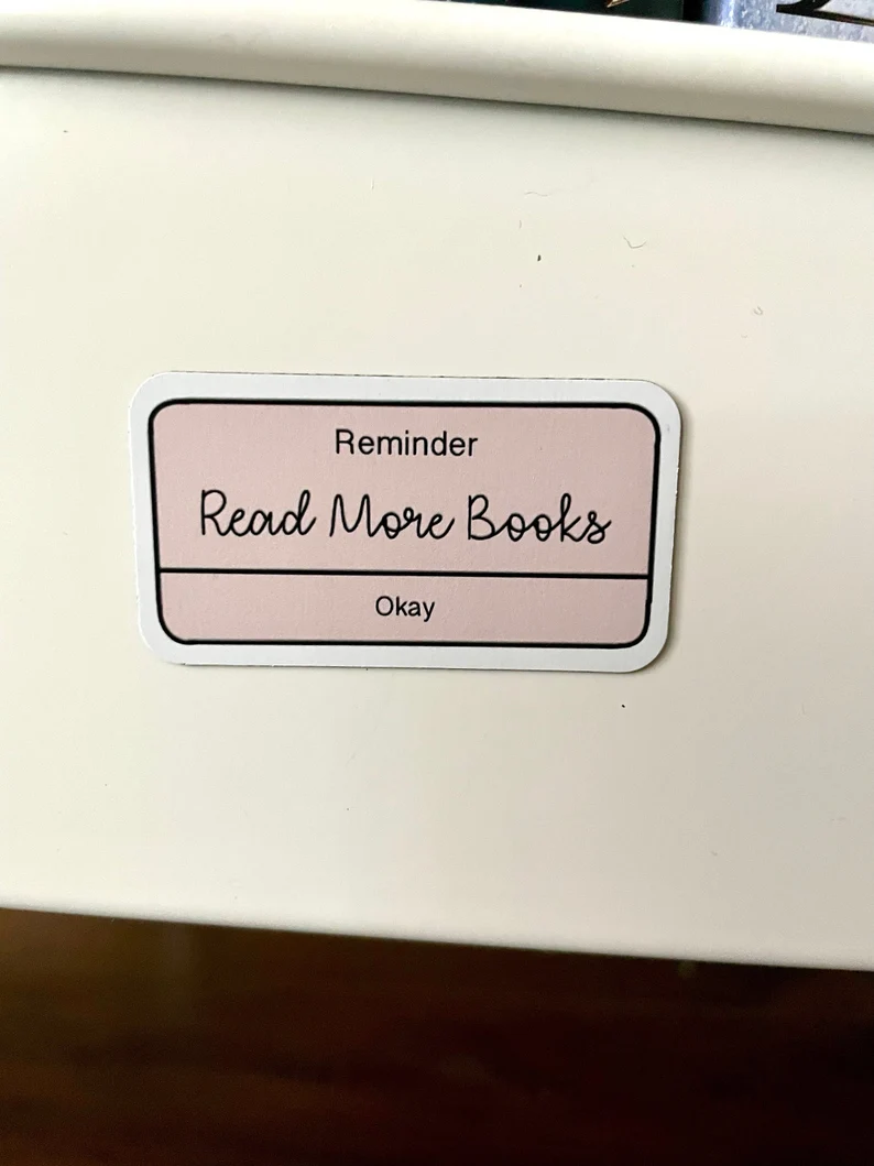 Image of a pink magnet designed like a pop up notification. It says "reminder: read more books. okay."