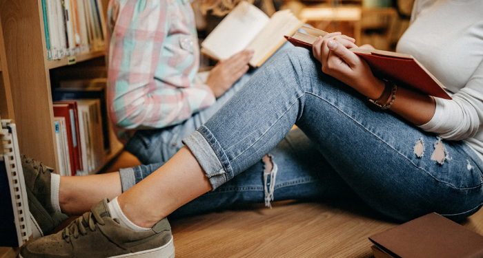 a photo of two people sitting on the floor of a bookstore and reading