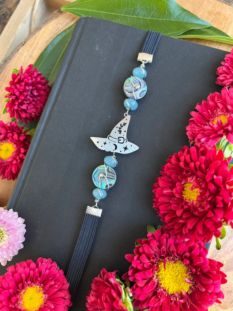 Image of a thong-style bookmark featuring a witch hat and gemstones. 