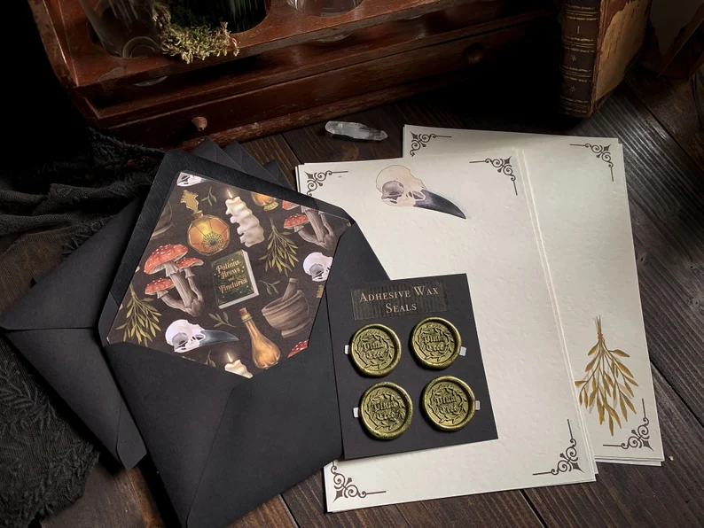 Image of a stationary set, including envelopes, paper, and adhesive seals featuring a witchy aesthetic. 
