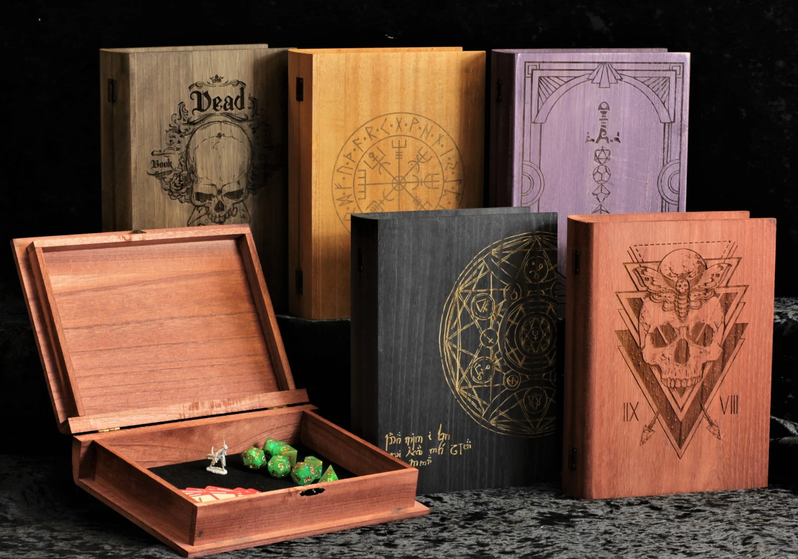 A photo of several custom book-shaped wooden dice boxes. The bottom left book-shaped wooden dice box contains several spell cards and dice as well as a miniature figure. 