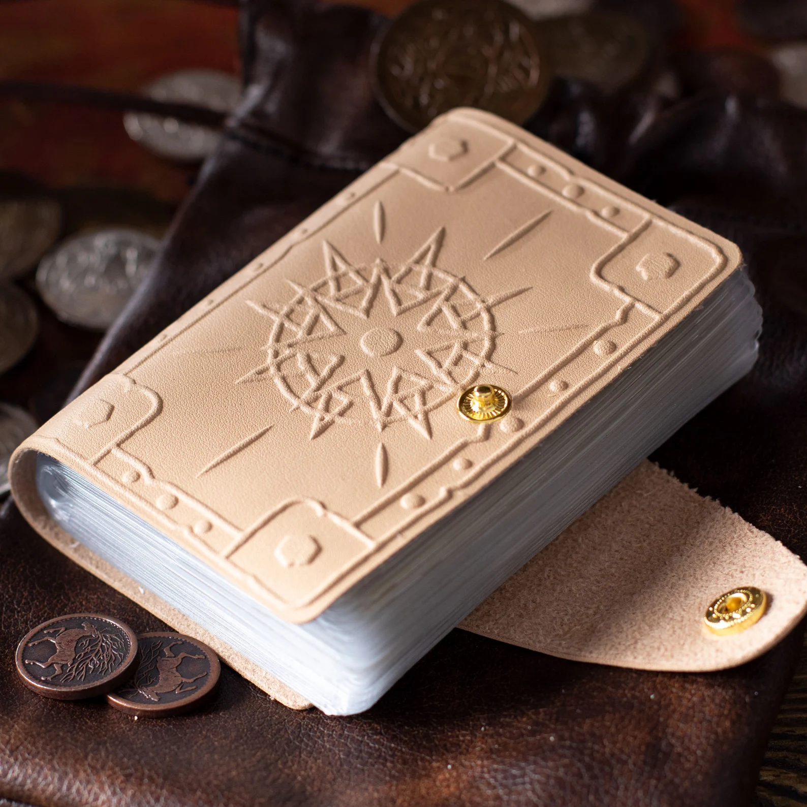 A photo of a cream-colored leather book with plastic spell card pages inside and a golden snap clasp.