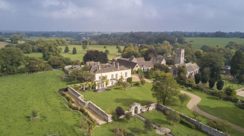 an aerial shot of the estate, showing several buildings, a walled in property, and a large manicured lawn