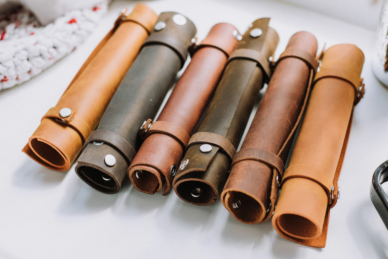 A photo of several leather scrolls held together with leather bands that snap together with silver fastenings. 