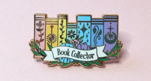 an enamel pin with a rainbow bookshelf and the text Book Collector