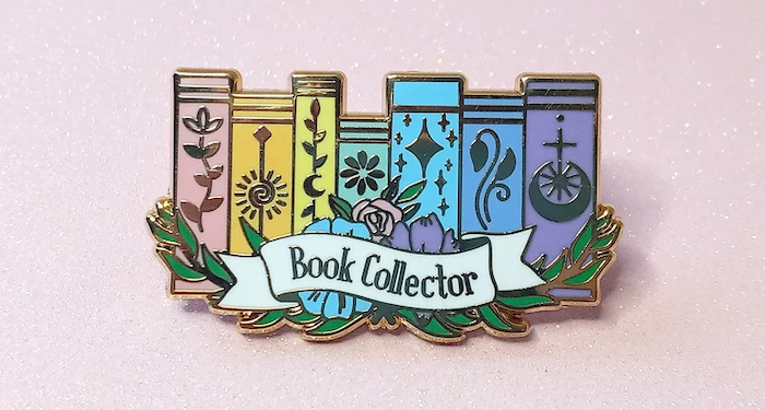 an enamel pin with a rainbow bookshelf and the text Book Collector