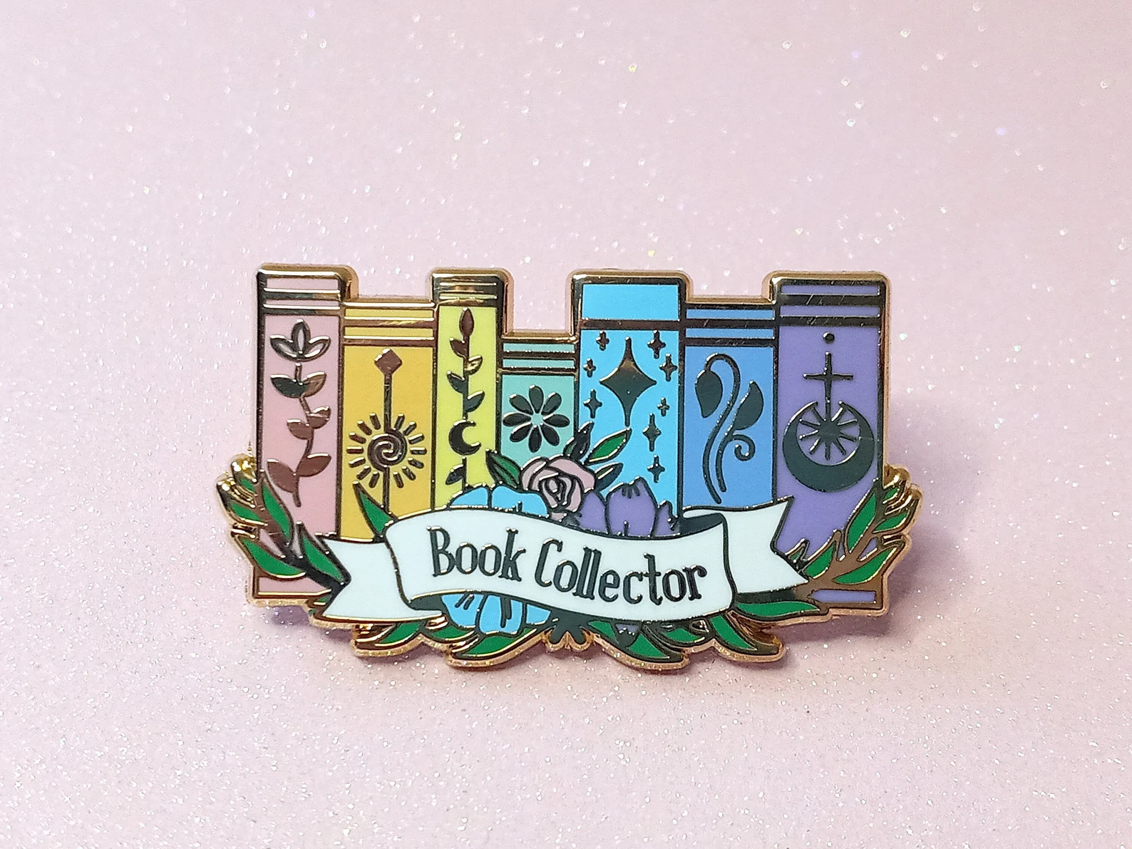 An enamel pin depicting a rainbow shelf with the words "Book Collector"