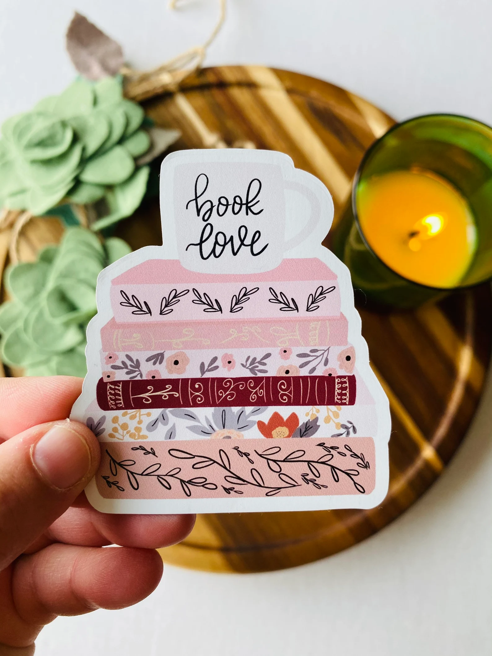 A vinyl sticker that depicts a stack of pink books with a mug that says "book love"