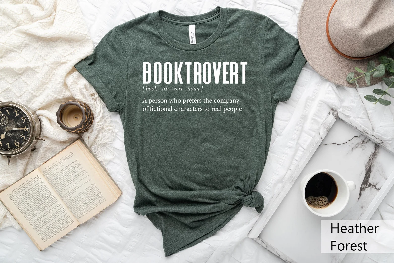 a green t-shirt that reads "Book trovert: a person who prefers the company of fictional characters to people"