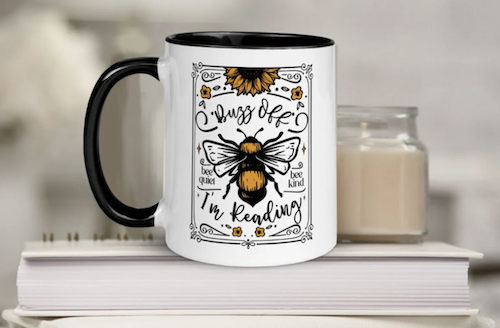 white mug black handle with illustration of bee that says buzz off I'm reading