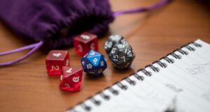 a pen, notebook, and dice in a purple velvet pouch to play a role-playing game like Dungeons and Dragons