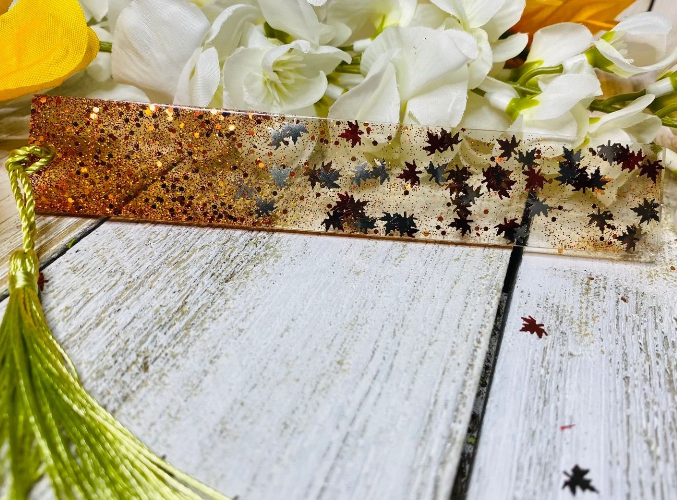Image of a resin bookmark with leave sparkles inside in a fall colorway. 