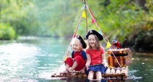 two small white children playing pirate adventure on wooden raft